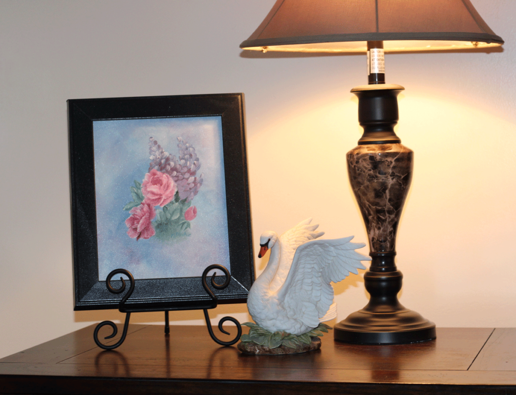 Rose painting on a table with a lamp and a swan figurine